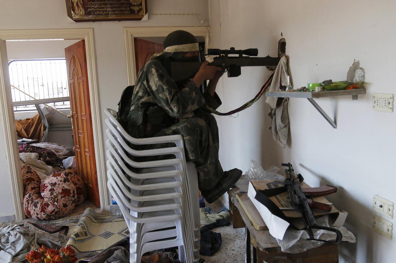A rebel fighter sits on chairs as he aims his weapon through a hole inside a house in the town of Morek in Hama province July 21, 2014. Picture taken July 21, 2014. REUTERS/Badi Khlif (SYRIA - Tags: POLITICS CIVIL UNREST CONFLICT TPX IMAGES OF THE DAY)