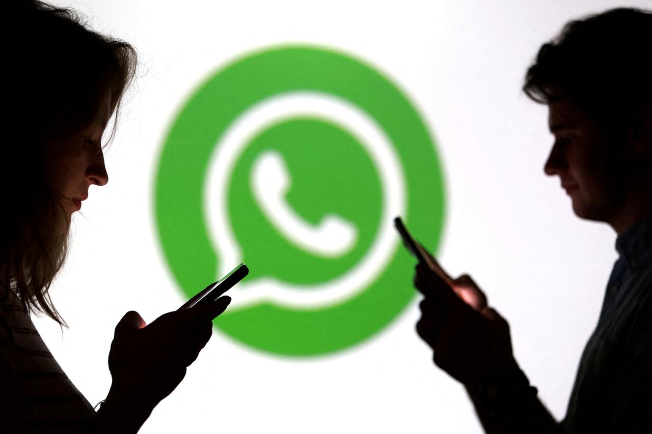 FILE PHOTO: Illustration shows teenagers pose for a photo while holding smartphones in front of a Whatsapp logo