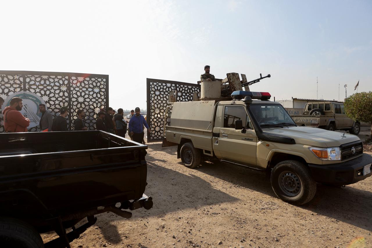 Members of an Iraqi Shi'ite armed group sit in a vehicle after an attack by a drone strike on an Iran-backed militia headquarters in Baghdad