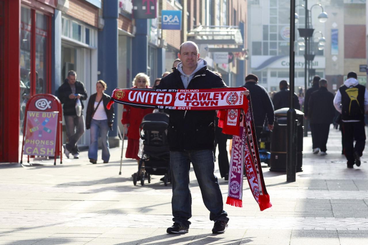\'A man sells Crawley Town Football Club souvenirs in the centre of Crawley, south of England, February 17, 2011. Crawley Town are due to play Manchester United in the fifth round of The FA Cup at Old
