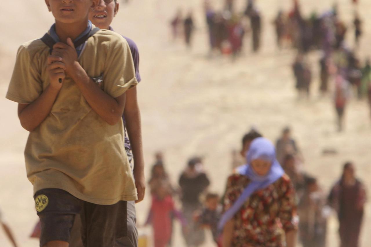 Displaced people from the minority Yazidi sect, fleeing the violence from forces loyal to the Islamic State in Sinjar town, walk towards the Syrian border, on the outskirts of Sinjar mountain, near the Syrian border town of Elierbeh of Al-Hasakah Governor
