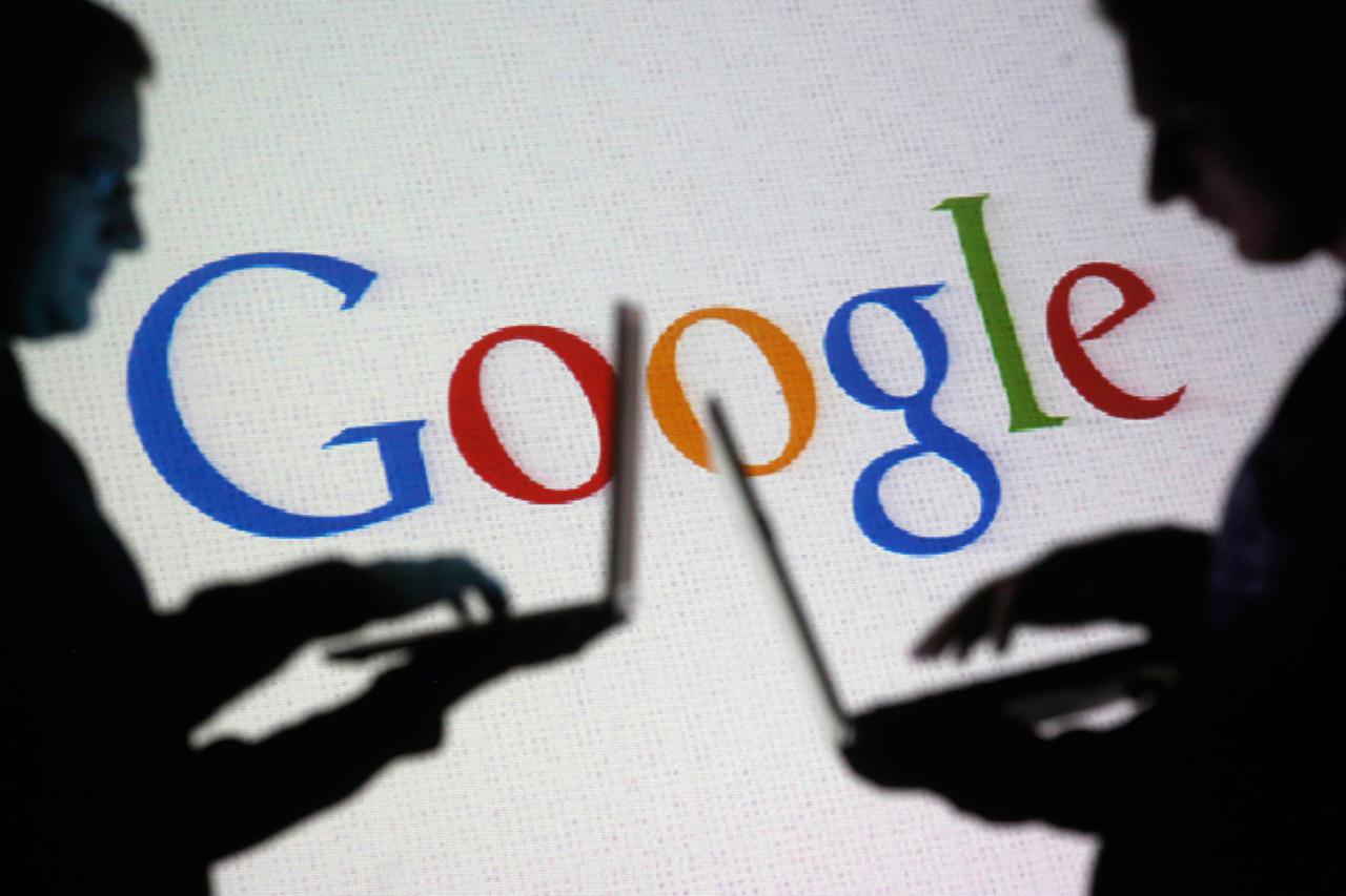 People are silhouetted as they pose with laptops in front of a screen projected with a Google logo, in this picture illustration taken in Zenica October 29, 2014.   Google Inc is changing its operating structure by setting up a new company called Alphabet