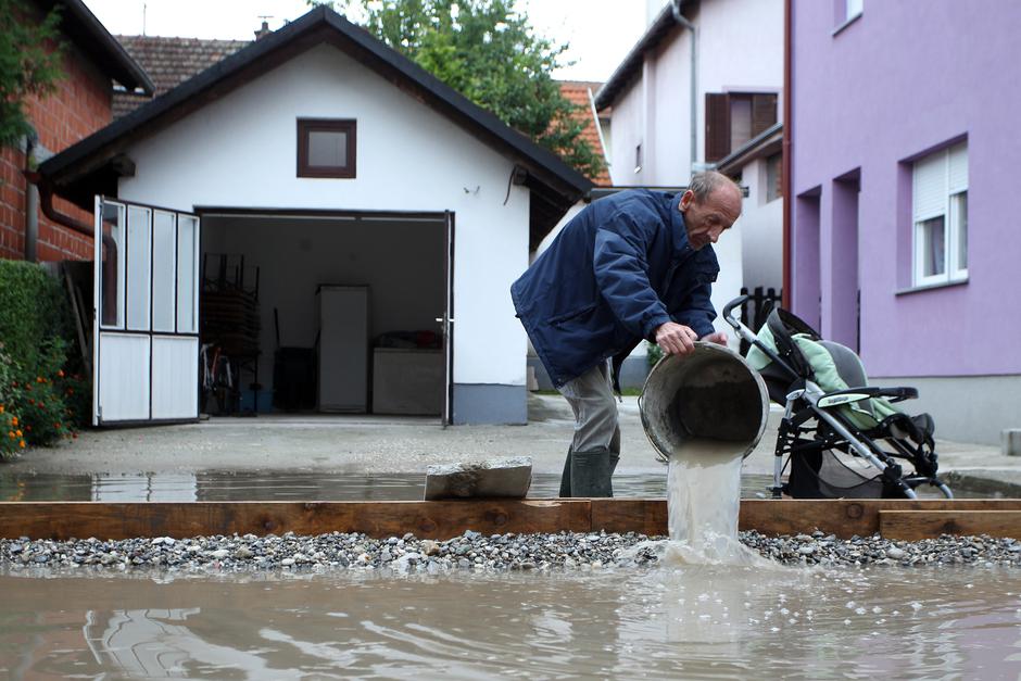 01.09.2014., Zagreb - Ulica Franje Malnara, IX. odvojak, stanari ne mogu van iz kuce cim padne malo oborina. Nemaju asfalt, ni kanalizaciju ni odvod koji im grad dugo obecava. Stanar Joza Krndija izbacuje vodu iz svog dvorista nakon kise koja je napadala 