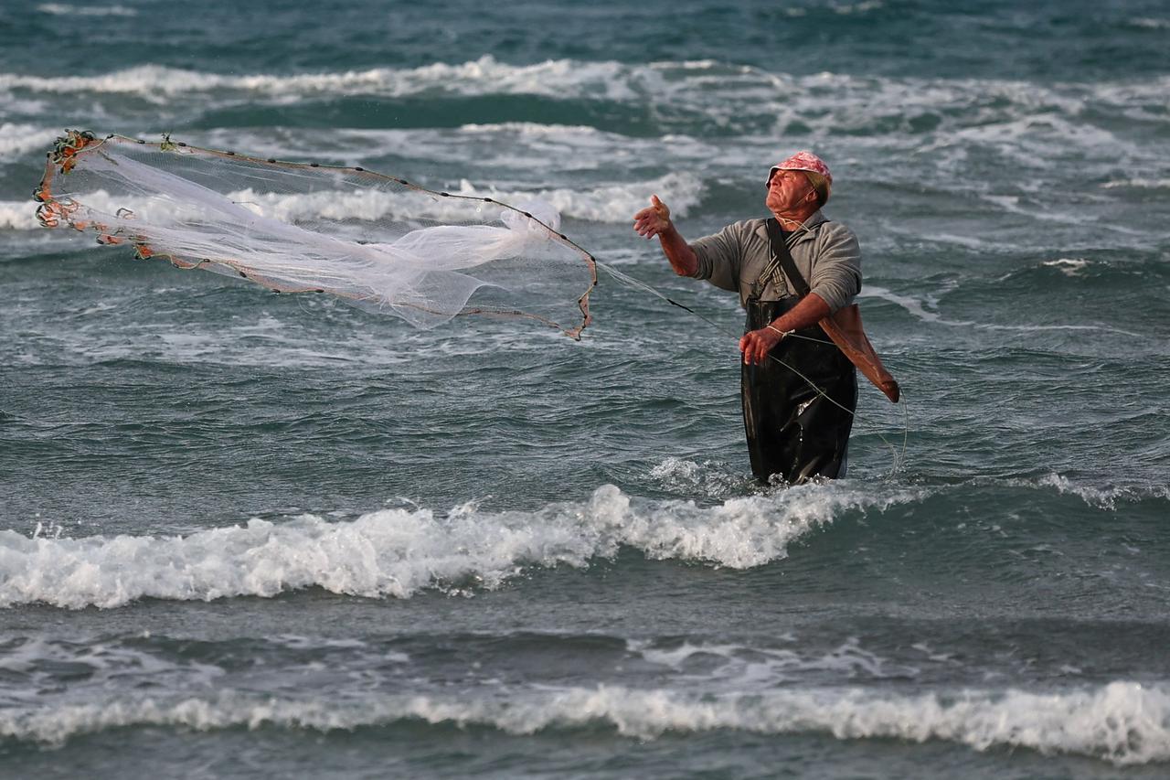 A fisherman throws his net at the sea in Vlora