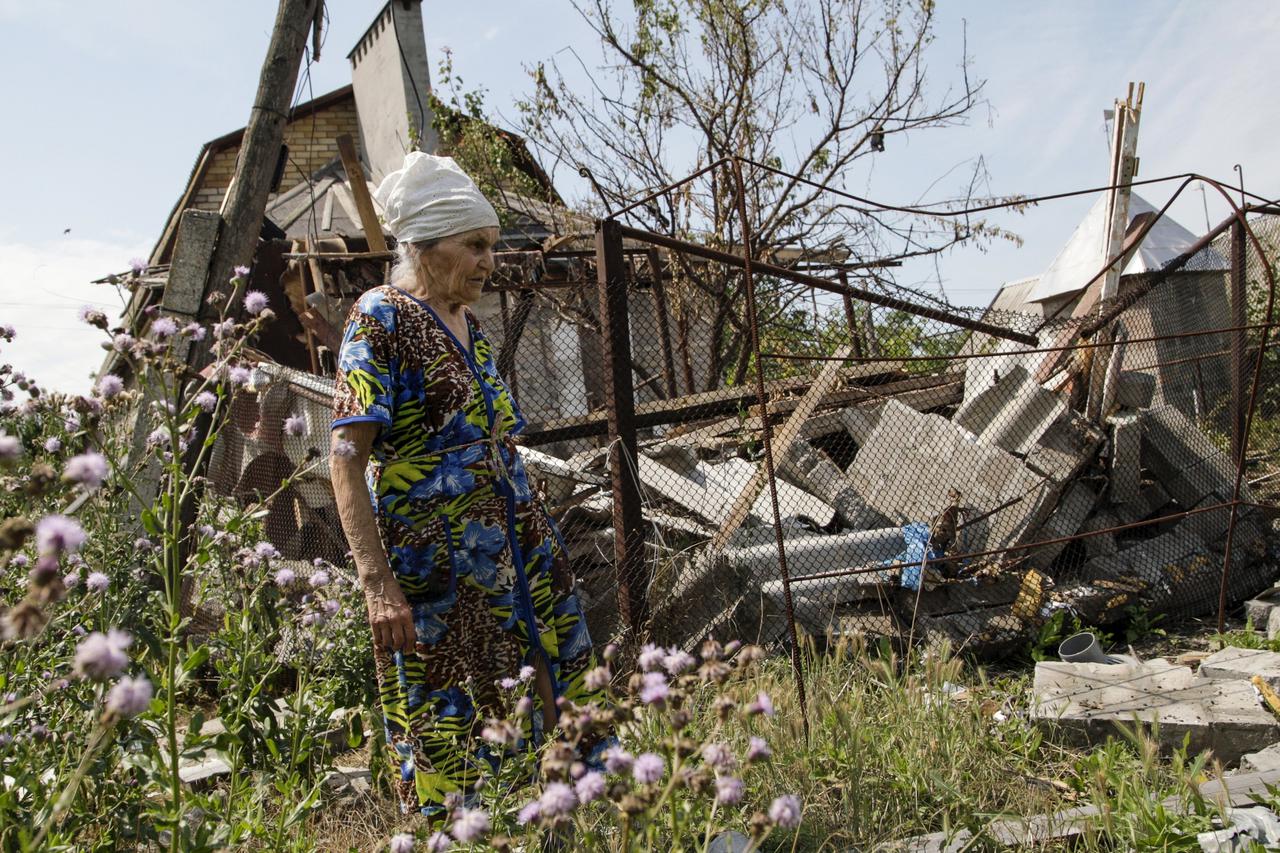A woman walks past her damaged house, which according to locals was hit by shelling on Wednesday, the village of Sakhanka in Donetsk region, Ukraine, July 2, 2015. REUTERS/Alexander Ermochenko      TPX IMAGES OF THE DAY