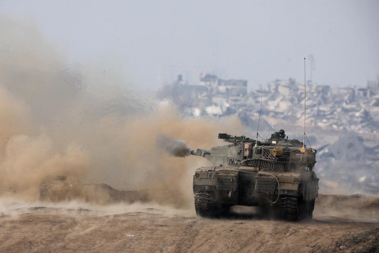 FILE PHOTO: An Israeli tank fires towards Gaza, at the Israel-Gaza border