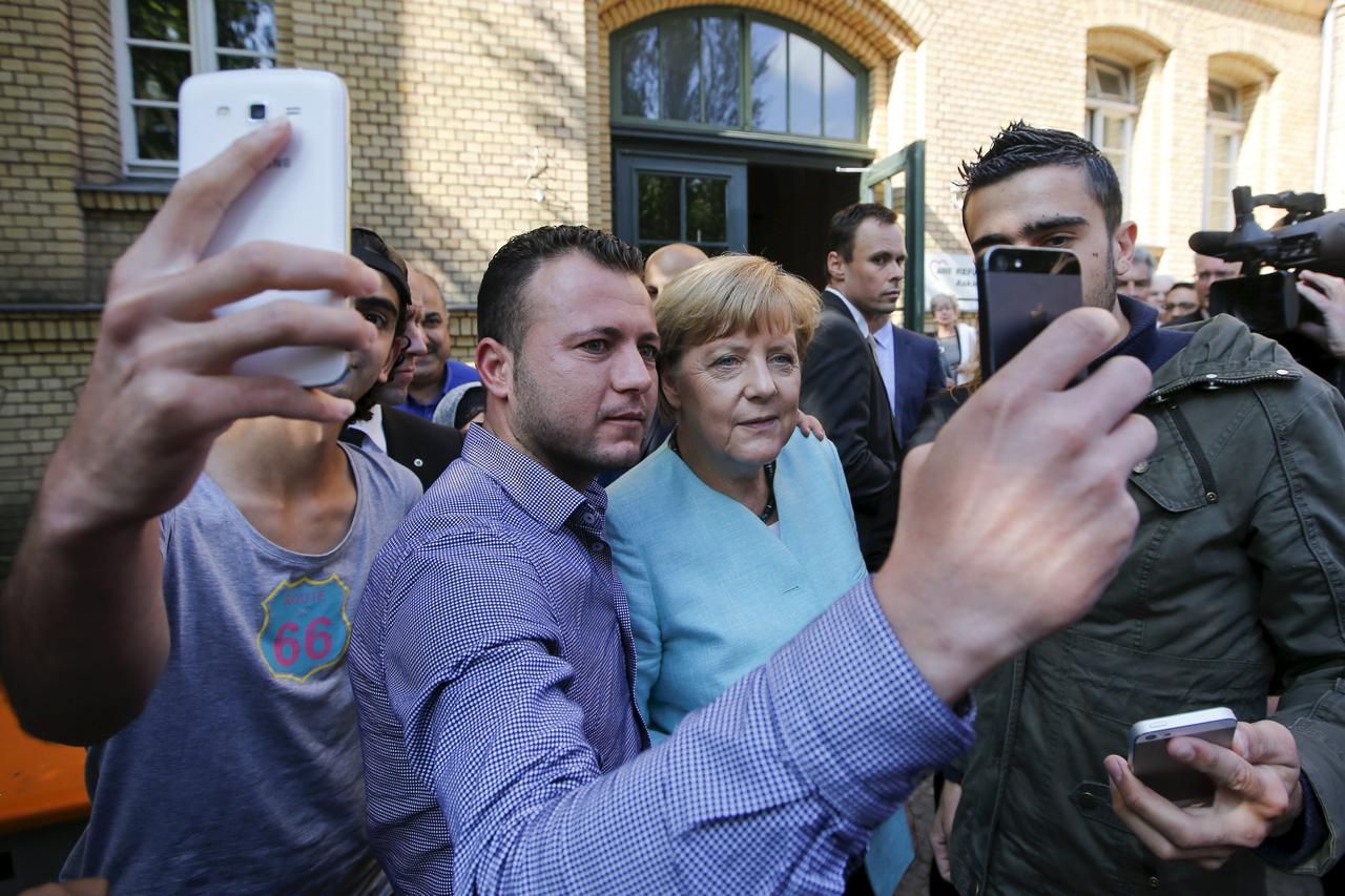 Migrants from Syria and Iraq take selfies with German Chancellor Angela Merkel outside a refugee camp near the Federal Office for Migration and Refugees after their registration at Berlin's Spandau district, Germany in this September 10, 2015 file photo. 