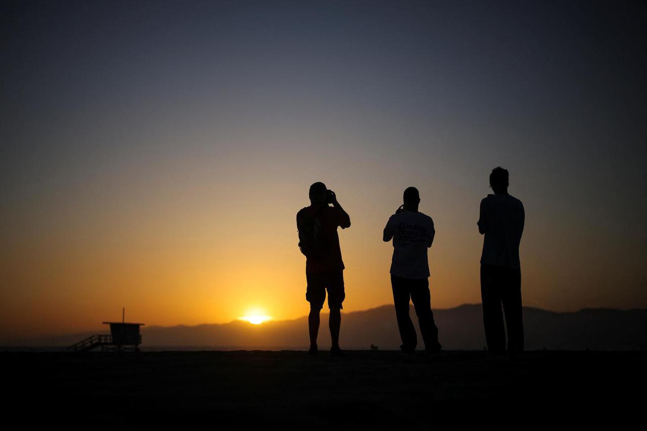 People watch the sun set at Venice Beach in Los Angeles