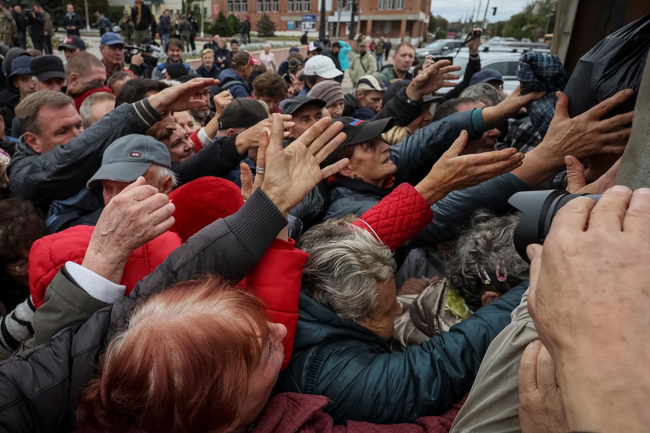 Local residents crowd near a car distributing humanitarian aid in the town of Balakliia