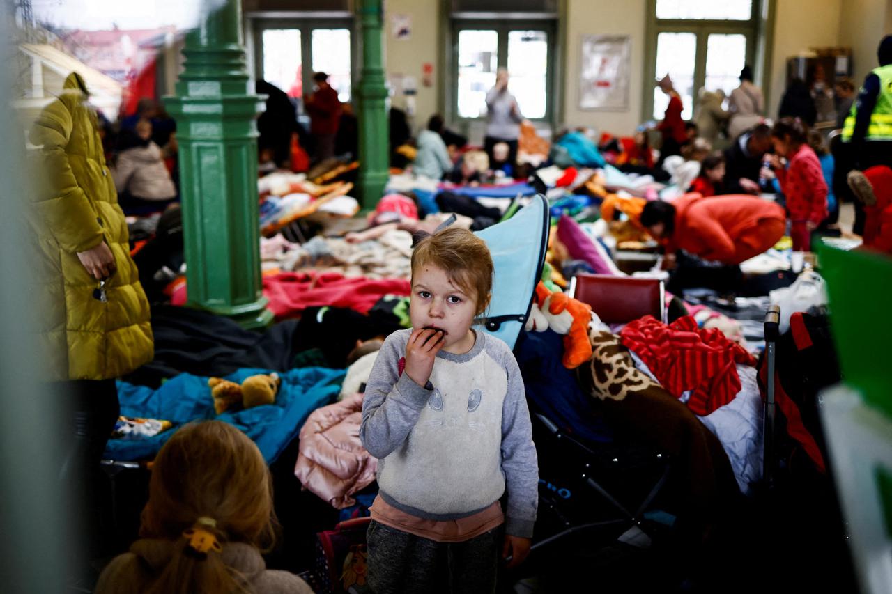FILE PHOTO: A child eats a cookie as she stands in a temporary accommodation for refugees at the train station, after fleeing Russian invasion of Ukraine, in Przemysl