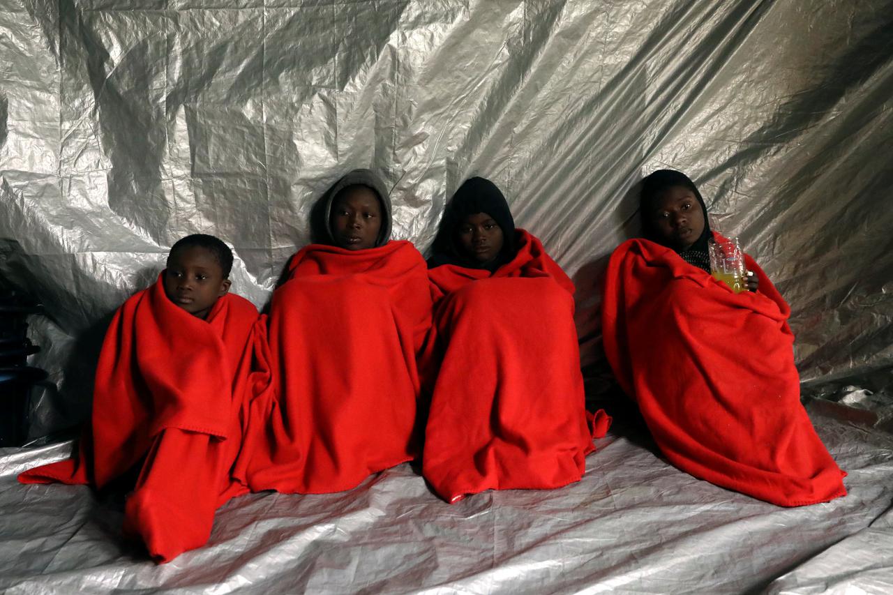 Migrants are covered with thermal blankets following a rescue operation of 104 sub-Saharan migrants aboard an overcrowded raft by the Spanish NGO Proactiva Open Arms, in the central Mediterranean Sea, 24 miles north of the Libyan coastal city of Sabratha,