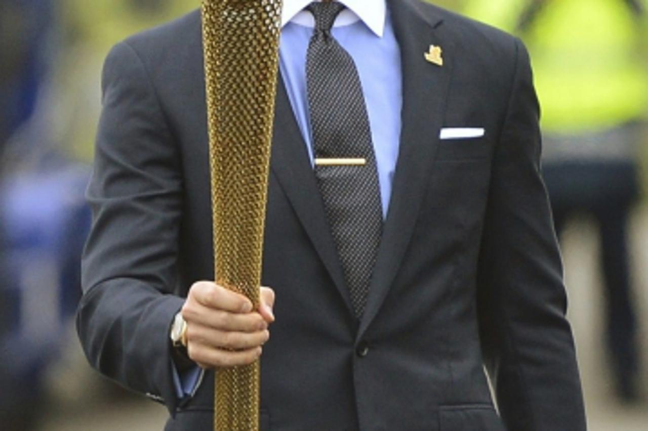 'British soccer player and London 2012 Olympic Games ambassador David Beckham carries the Olympic torch after arriving at RNAS Culdrose base near Helston in Cornwall, south west England May 18, 2012. 