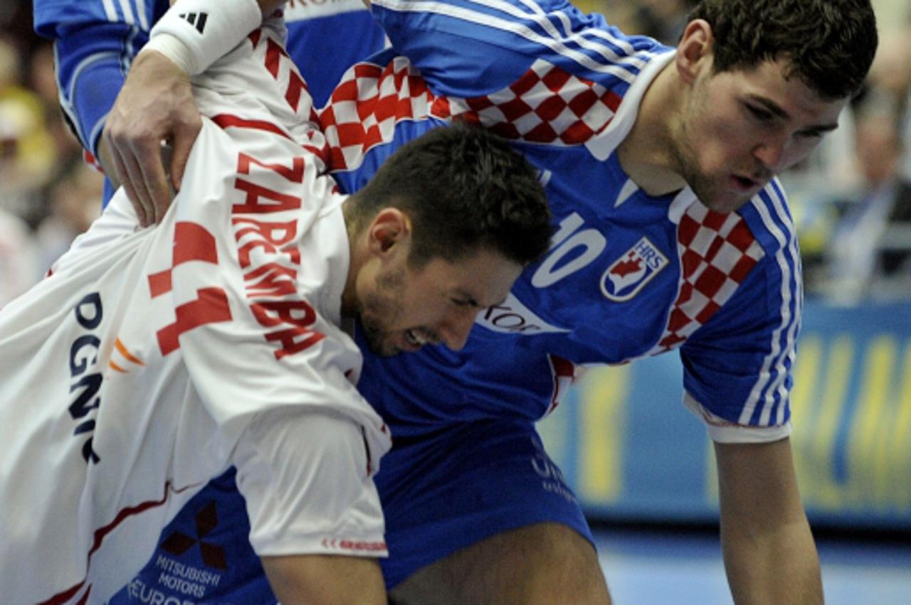 'Poland\'s Mateusz Zaremba (L) is pushed by Croatia\'s Jakov Gojun (R) during Men\\u0092s Handball World Championships between their teams on January 25, 2011 at the Malmo Arena.  AFP PHOTO / ATTILA K