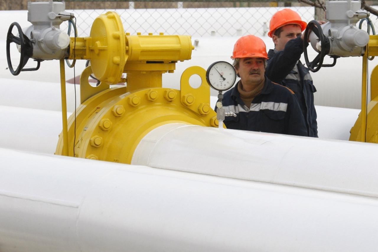 'Workers stand near pipes at a gas compressor station in the Ukrainian settlement of Orlovka, about 280 km (174 miles) west of the Black Sea port of Odessa, January 14, 2009. Russia\'s gas export mono