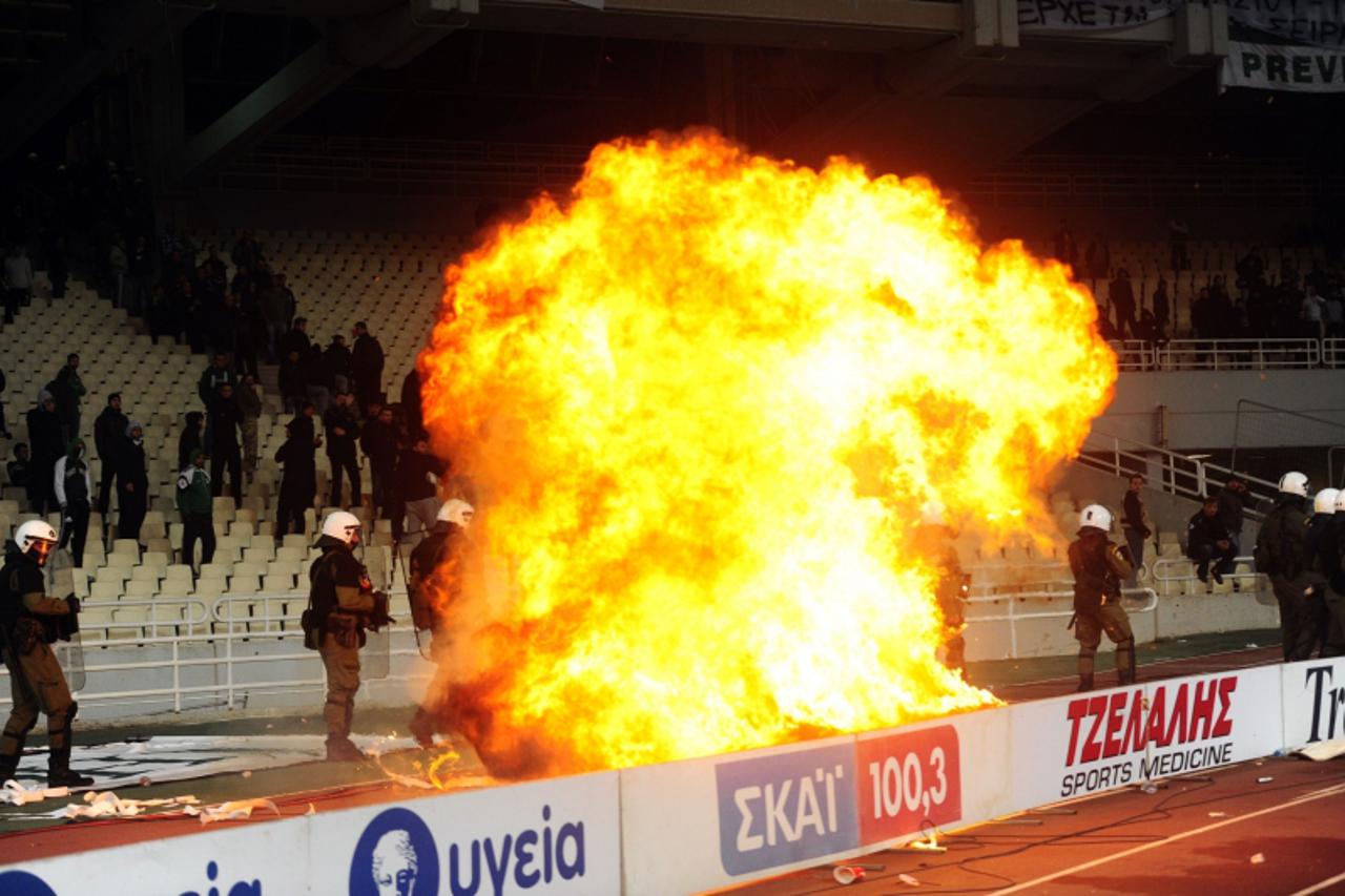 'Greek riot police watch a fire set by a petrol bomb as they clash with Panathinaikos supporters during a Greek Super League football game against Olympiakos in Athens on March 18, 2012.   AFP PHOTO/ 
