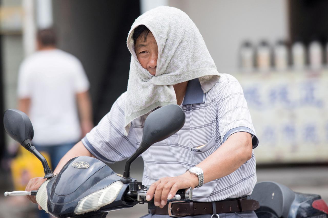 FILE PHOTO: A man is seen with a towel tied around his head to escape hot weather as a heat wave hits Hangzhou