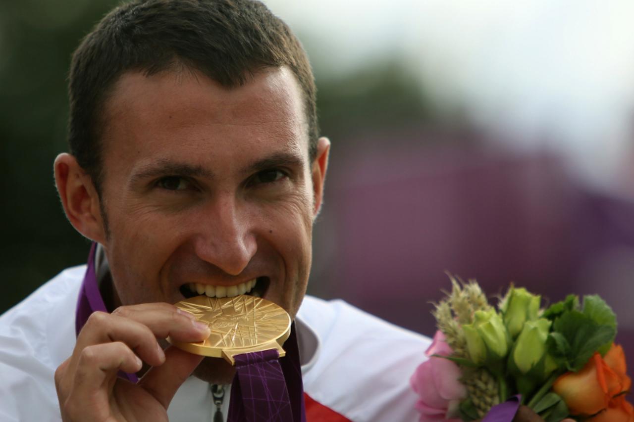 'Croatia\'s Giovanni Cernogoraz winner of the gold medal in the men\'s trap final at the London 2012 Olympic Games bites his medal on the podium at the  Royal Artillery Barracks in London on August 6,
