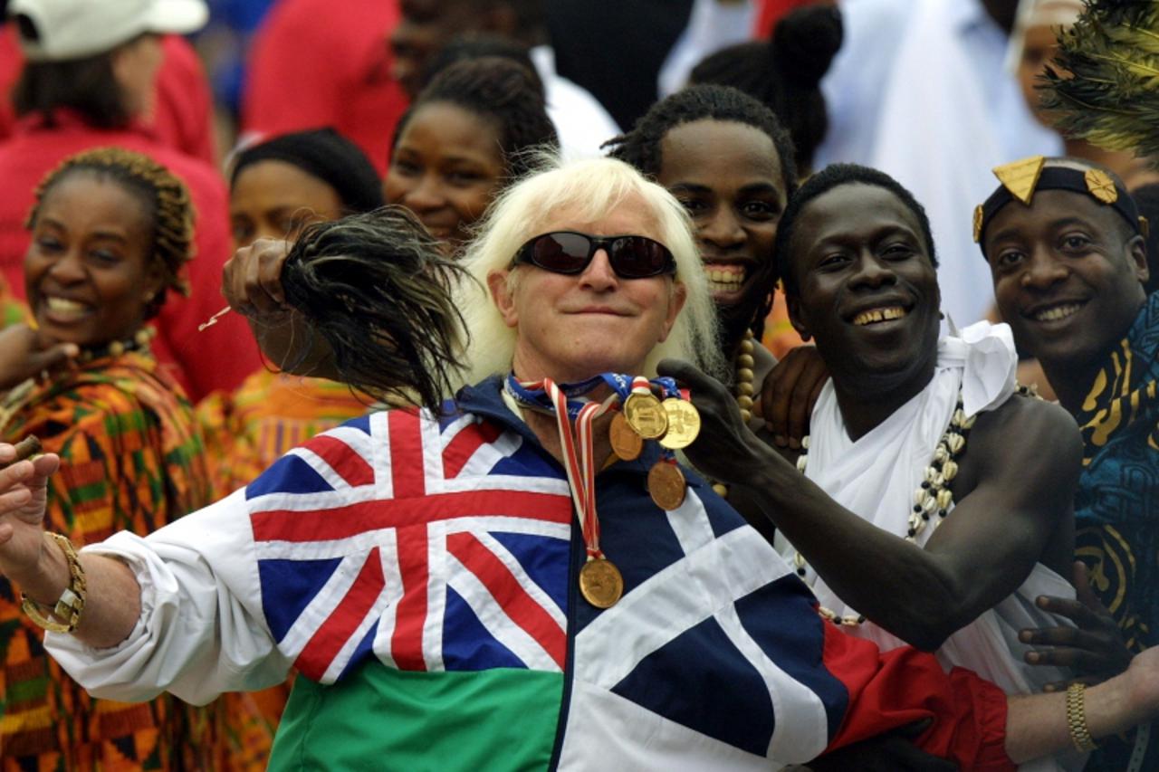 '(FILES) In this file picture taken on June 4, 2002 Jimmy Savile, a television and radio celeberity joins in with people representing Commonwealth countries wearing their tradional dress crowd into th