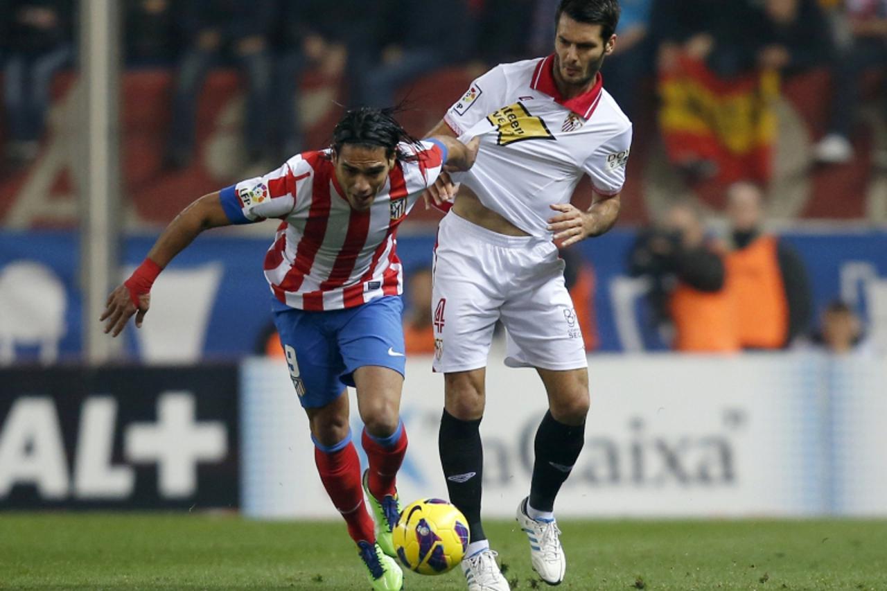 'Atletico Madrid's Radamel Falcao (L) and Sevilla's Emir Spahic fight for the ball during their Spanish first division soccer match at Vicente Calderon stadium in Madrid November 25, 2012.  REUTERS/