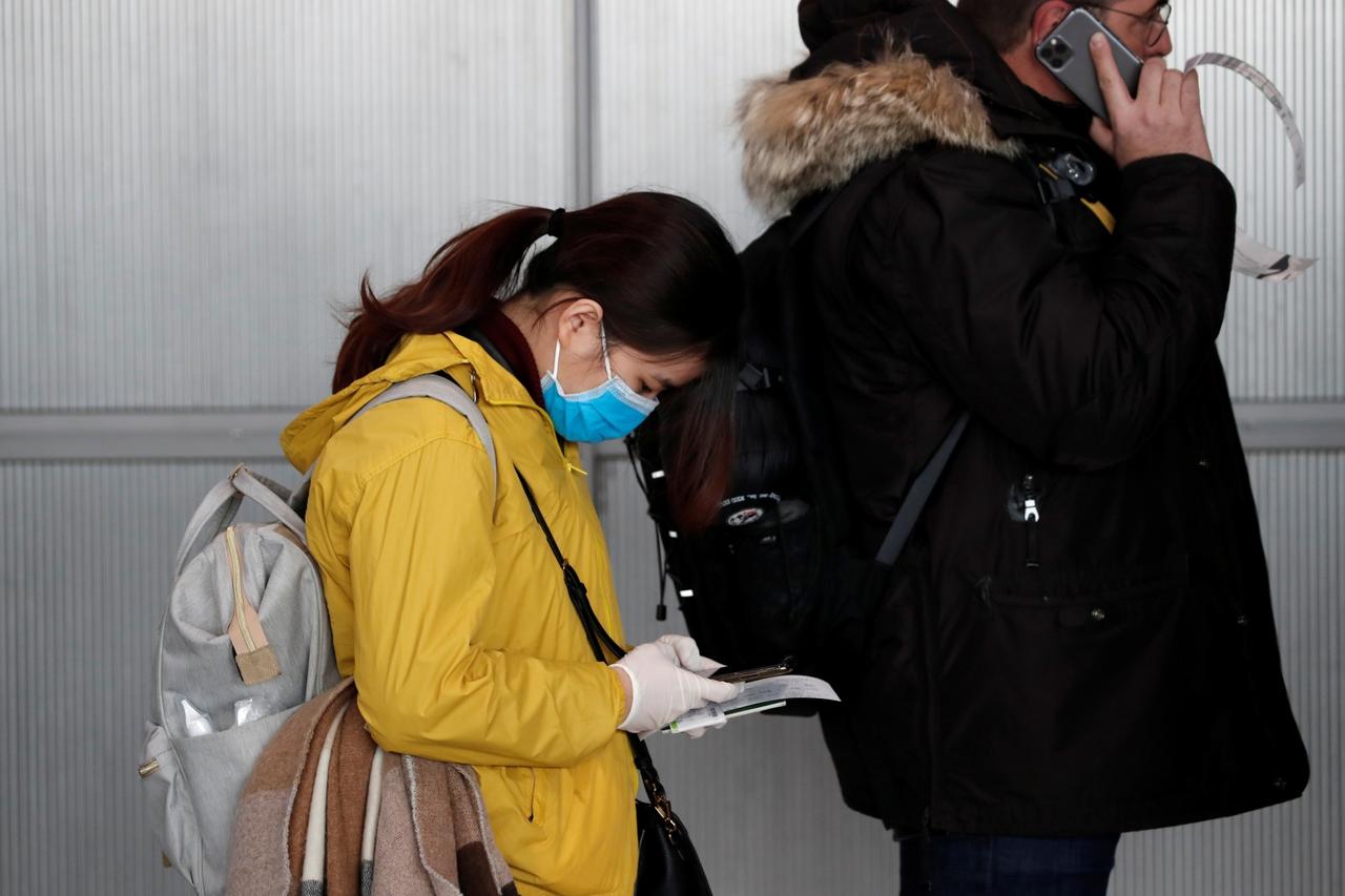 A woman wearing a protective face mask lines up at the Air France ticketing desk inside Terminal 2E at Paris Charles de Gaulle airport