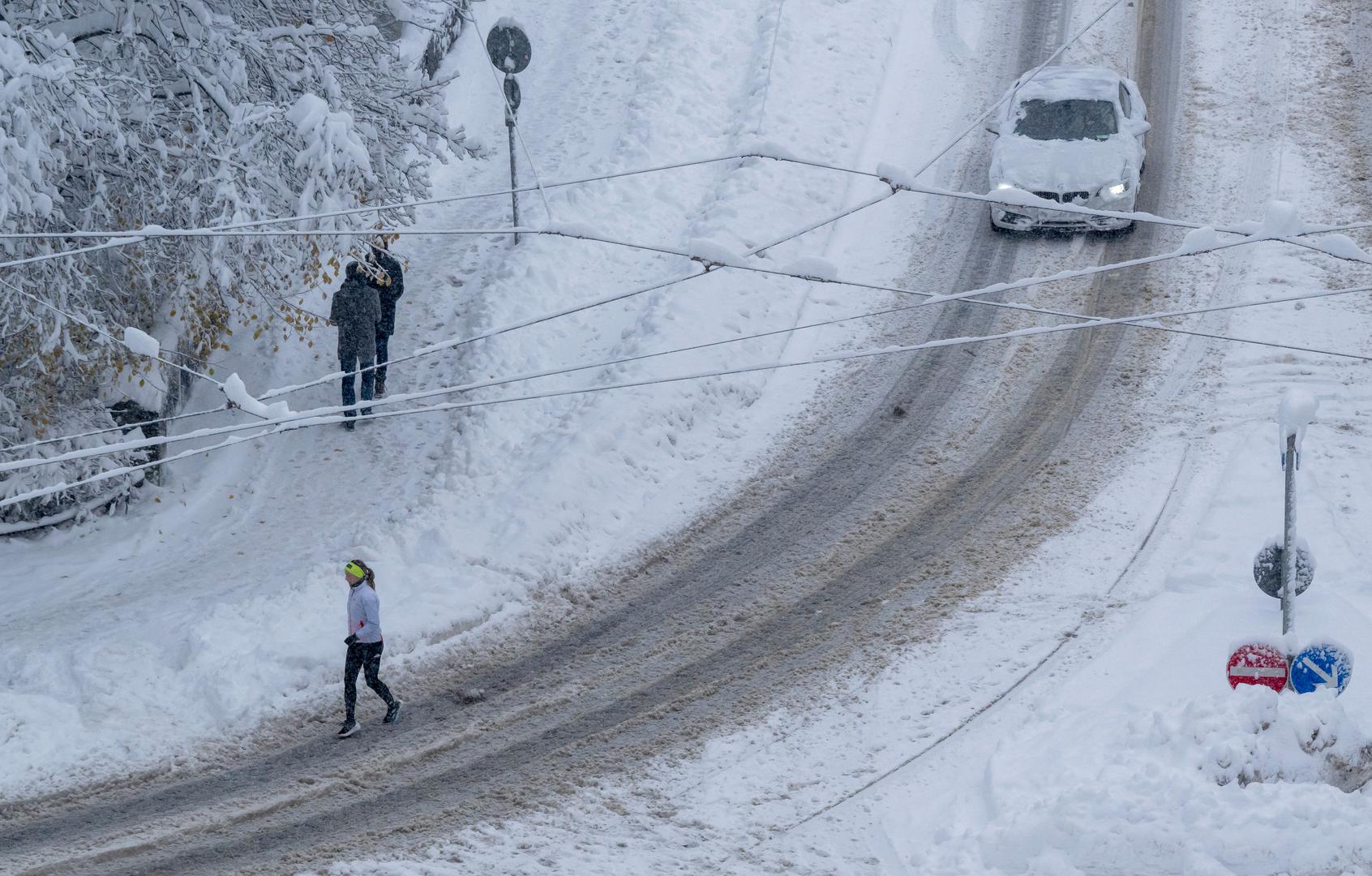 02 December 2023, Bavaria, Munich: A woman jogs across a snow-covered road. Snow and ice have caused chaos on the roads and on the railroads in southern Bavaria. Photo: Peter Kneffel/dpa Photo: Peter Kneffel/DPA