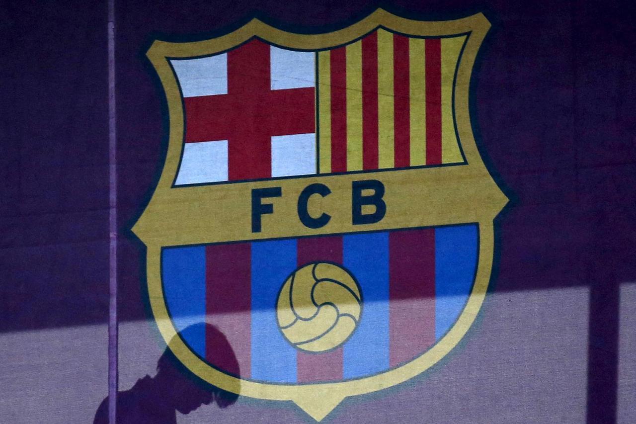 FILE PHOTO: A silhouette of a woman walks past behind a FC Barcelona's logo at Camp Nou stadium in Barcelona