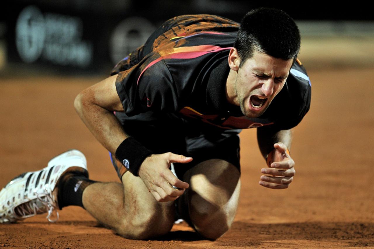 \'Novak Djokovic of Serbia falls to the ground during his ATP Rome Open tennis tournament semifinal match against Britain\'s Andy Murray (not seen) in Rome\'s Foro Italico on May 14, 2011. Djokovic be