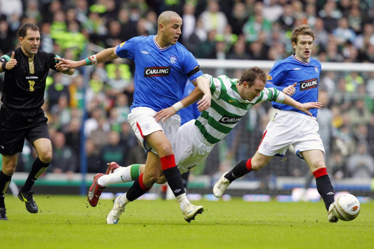 'Celtic\'c Aiden McGeady (C) falls forward as Rangers\' Madjid Bougherra (L) challenges during their \'Old Firm\' soccer match at Ibrox stadium in Glasgow, Scotland February 28, 2010. REUTERS/David Mo