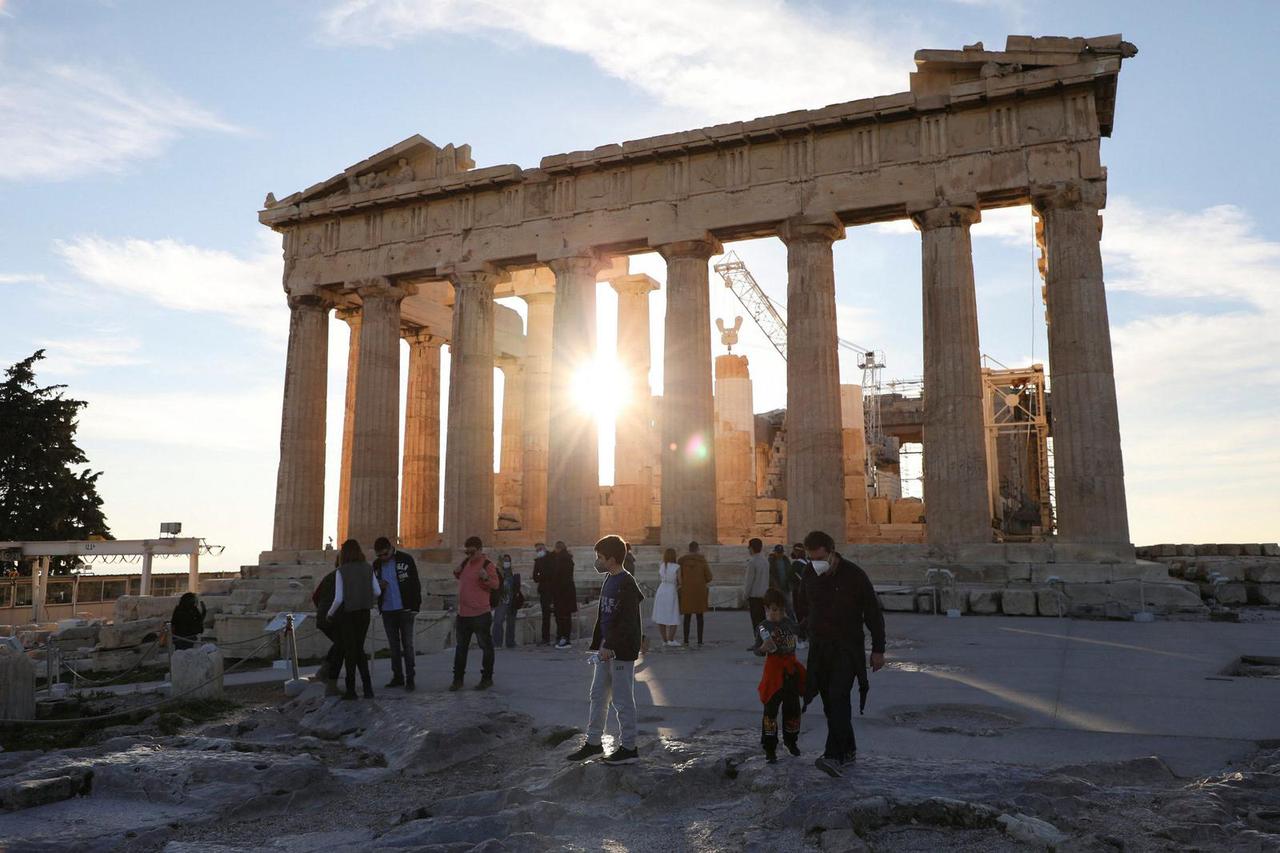 People wearing protective face masks make their way next to the Parthenon temple atop the Acropolis hill, in Athens