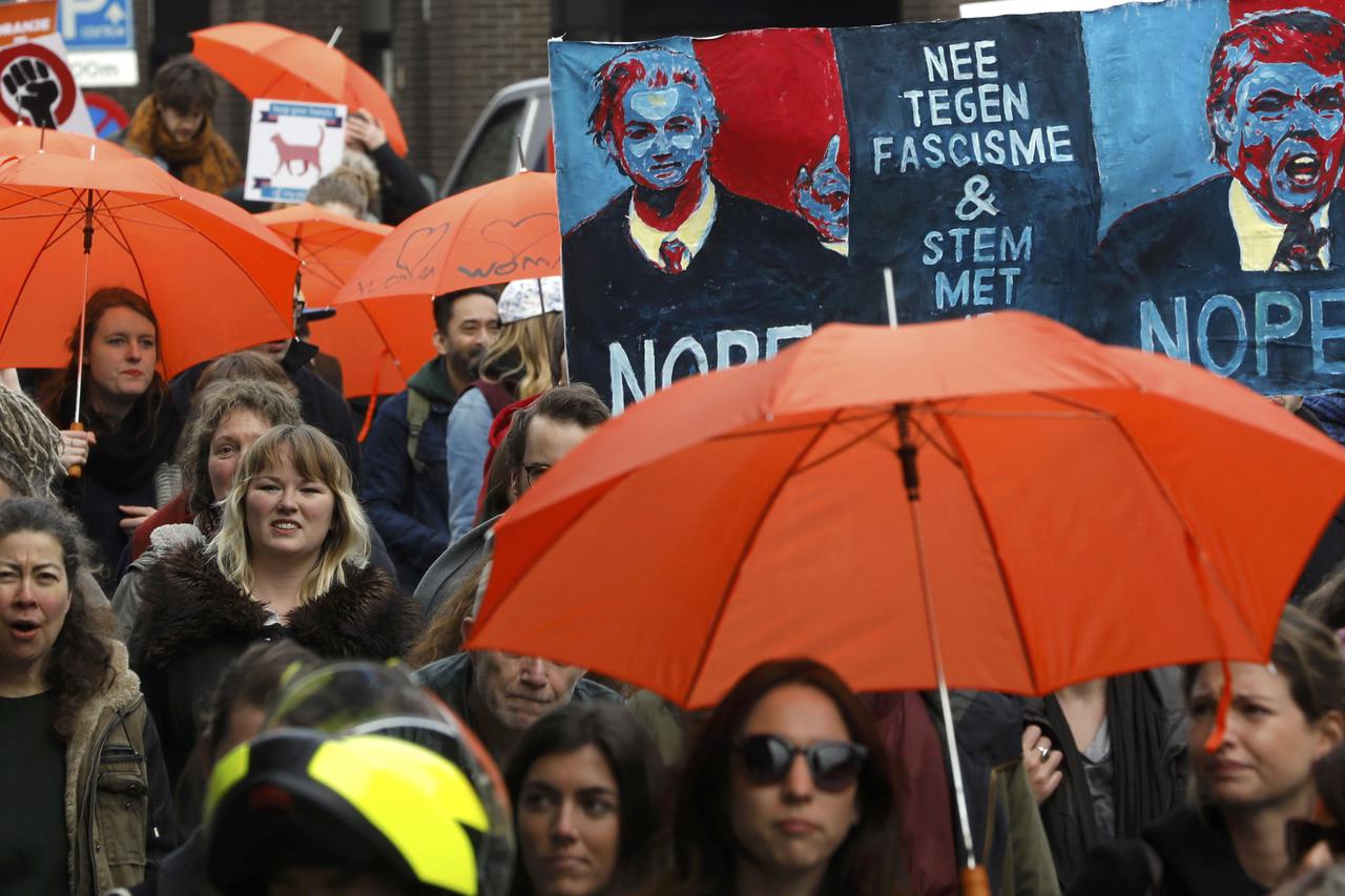 Demonstrators carrying orange umbrellas and signs reading 