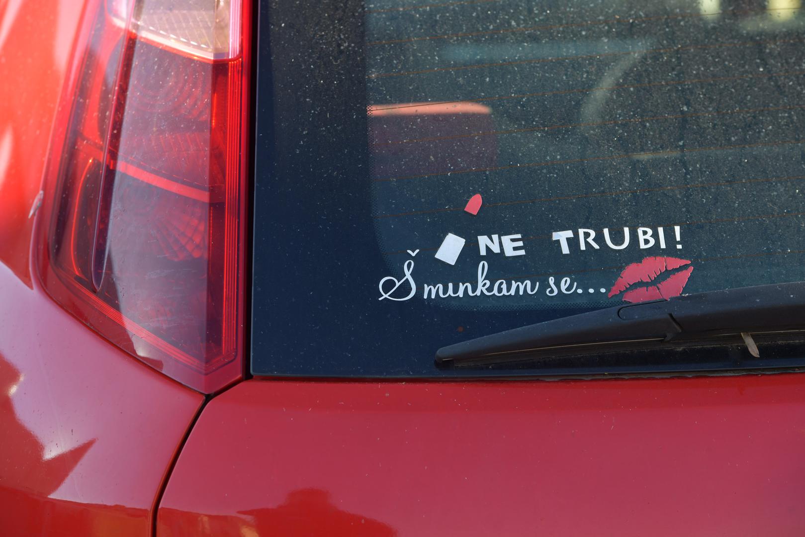 “Ne trubi! Šminkam se...” uz otisak crvenih usana i crtež ruža.