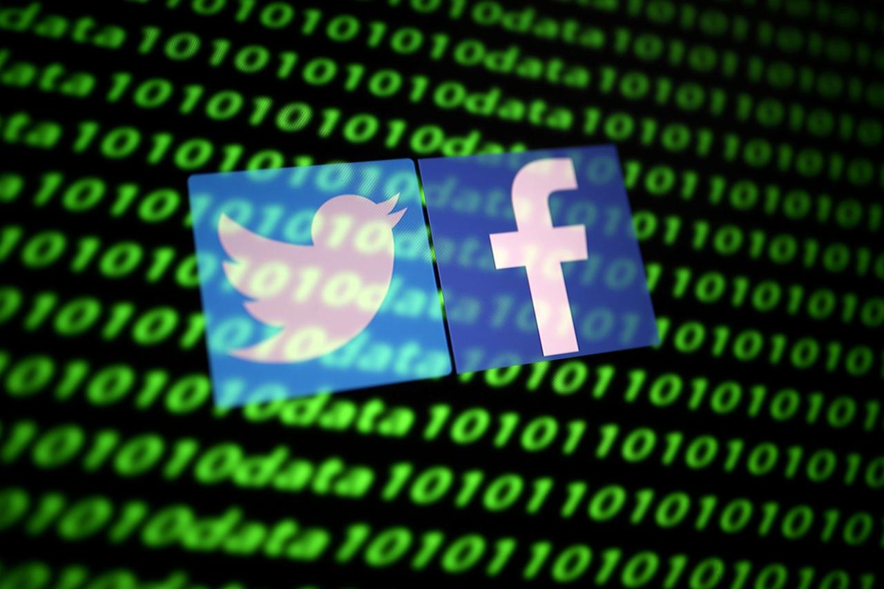 FILE PHOTO: The Twitter and Facebook logos along with binary cyber codes are seen in this illustration