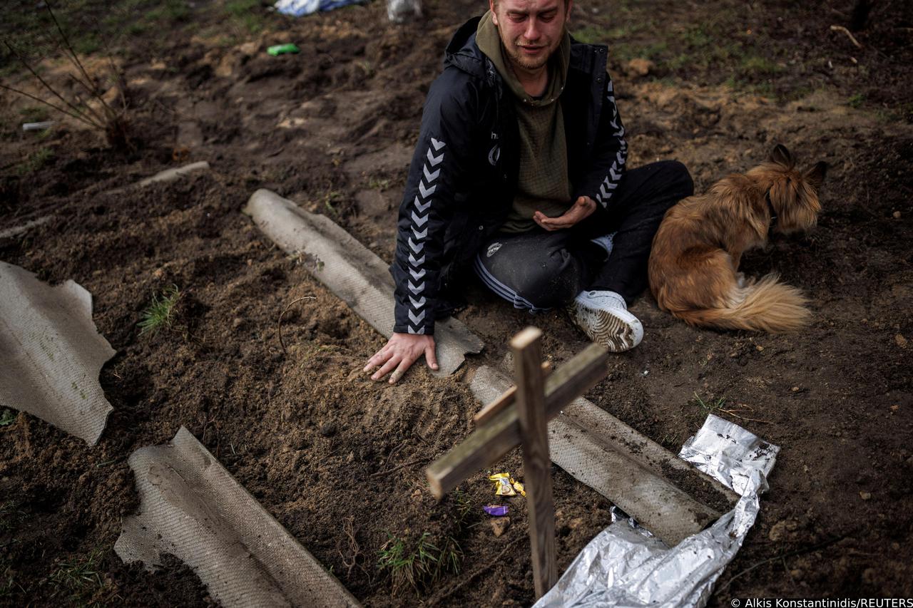 Serhii Lahovskyi mourns next to the grave of his friend Ihor Lytvynenko, in Bucha