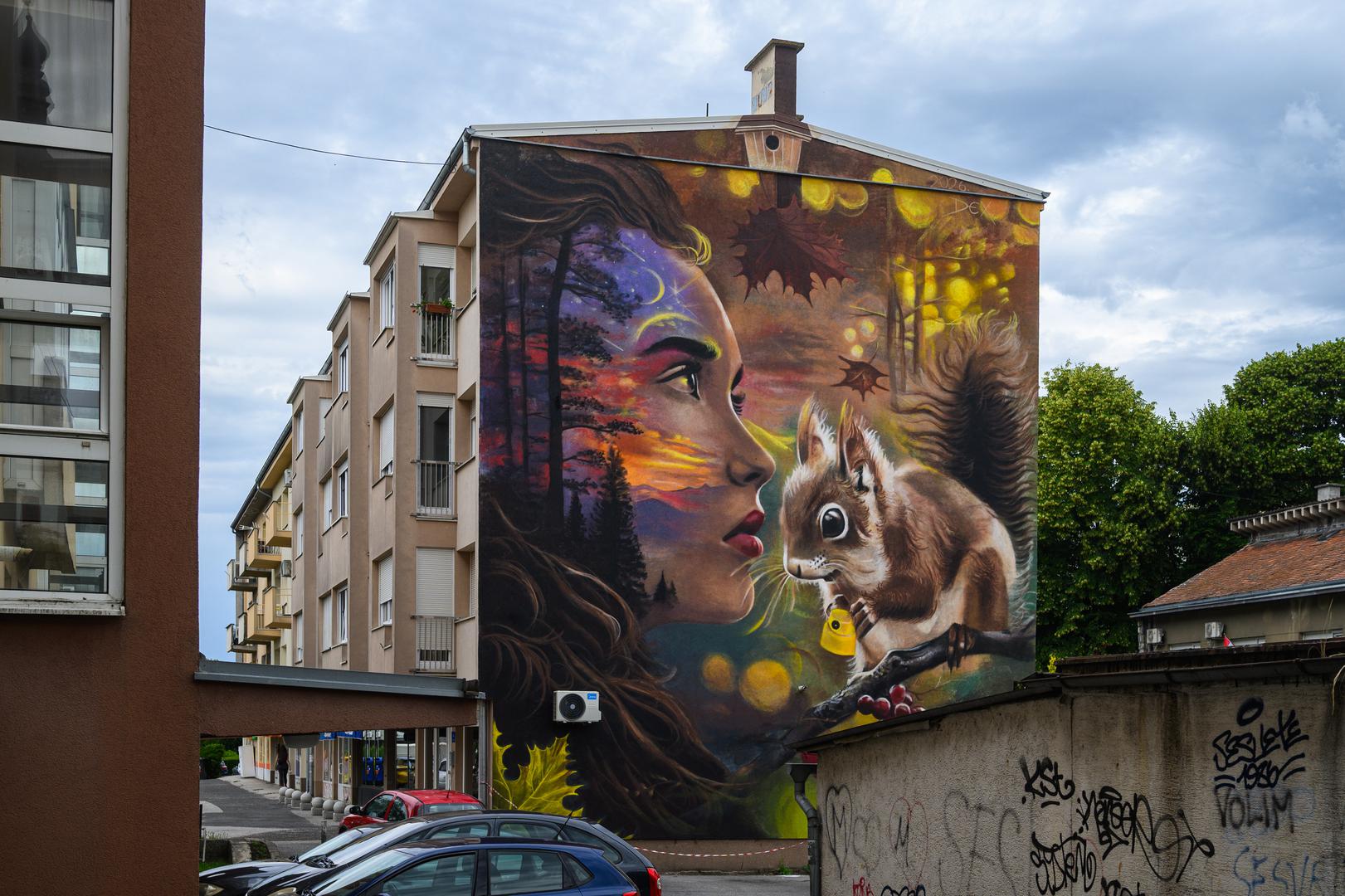 Zagrebačko naselje Sesvete odnedavno je bogatije za impresivno umjetničko djelo koje je transformiralo vizuru jedne od stambenih zgrada u Zagrebačkoj ulici. Na dojučerašnjoj sivoj fasadi osvanuo je mural koji prikazuje djevojku i vjevericu, rad svestranog umjetnika Dejana Šebestijana