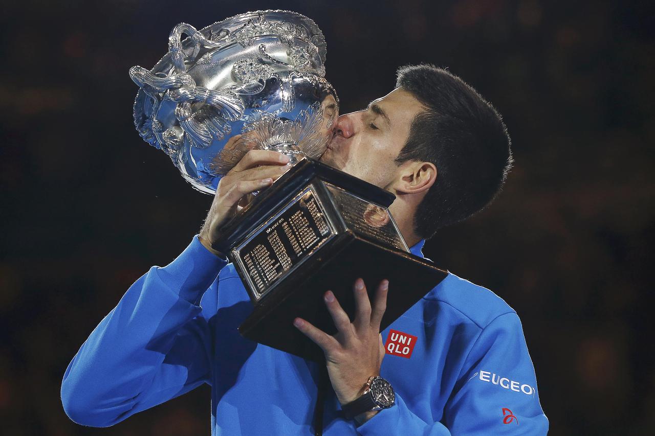 Novak Djokovic of Serbia kisses his trophy after defeating Andy Murray of Britain to win their men's singles final match at the Australian Open 2015 tennis tournament in Melbourne February 1, 2015.   REUTERS/Issei Kato (AUSTRALIA  - Tags: SPORT TENNIS)