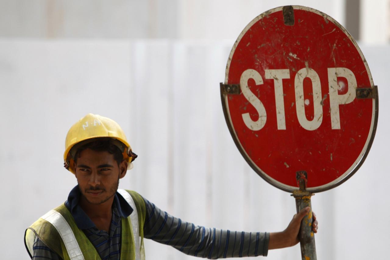 'A foreign worker directs traffic along a busy construction site in Singapore, March 12, 2013. REUTERS/Edgar Su (SINGAPORE - Tags: BUSINESS EMPLOYMENT CONSTRUCTION SOCIETY)'