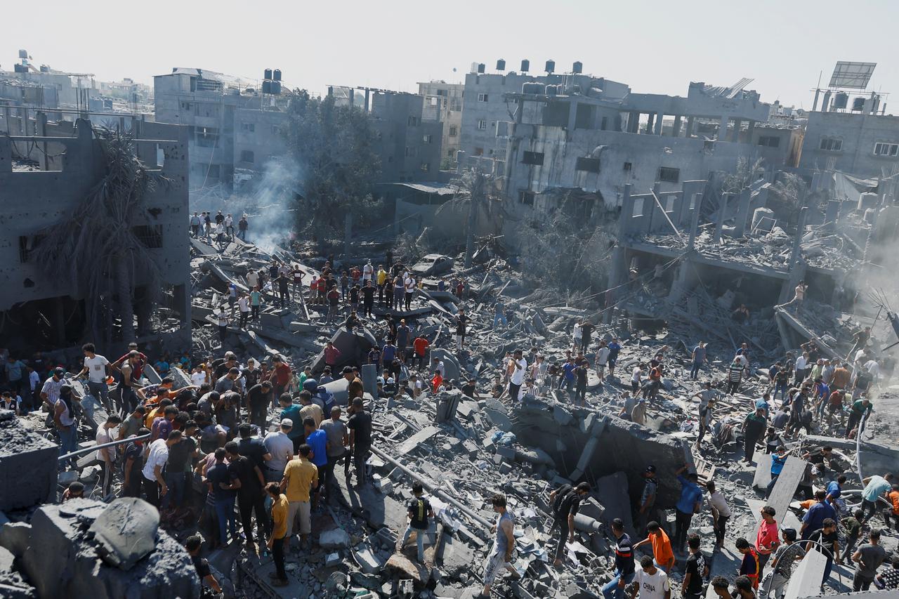Palestinians search for casualties at the site of Israeli strikes on houses, in Khan Younis