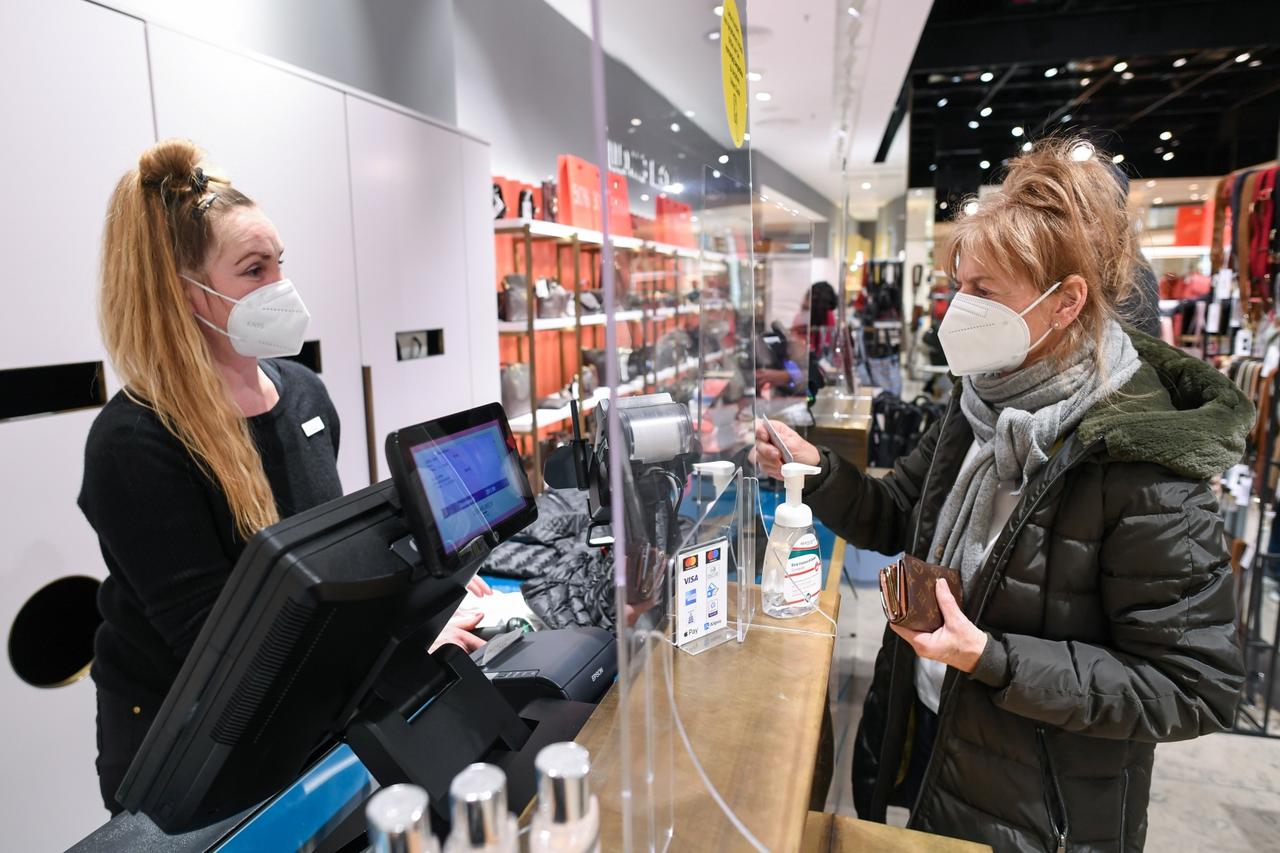 A customer pays for her purchases in a department store after the re-opening of certain businesses in Munich