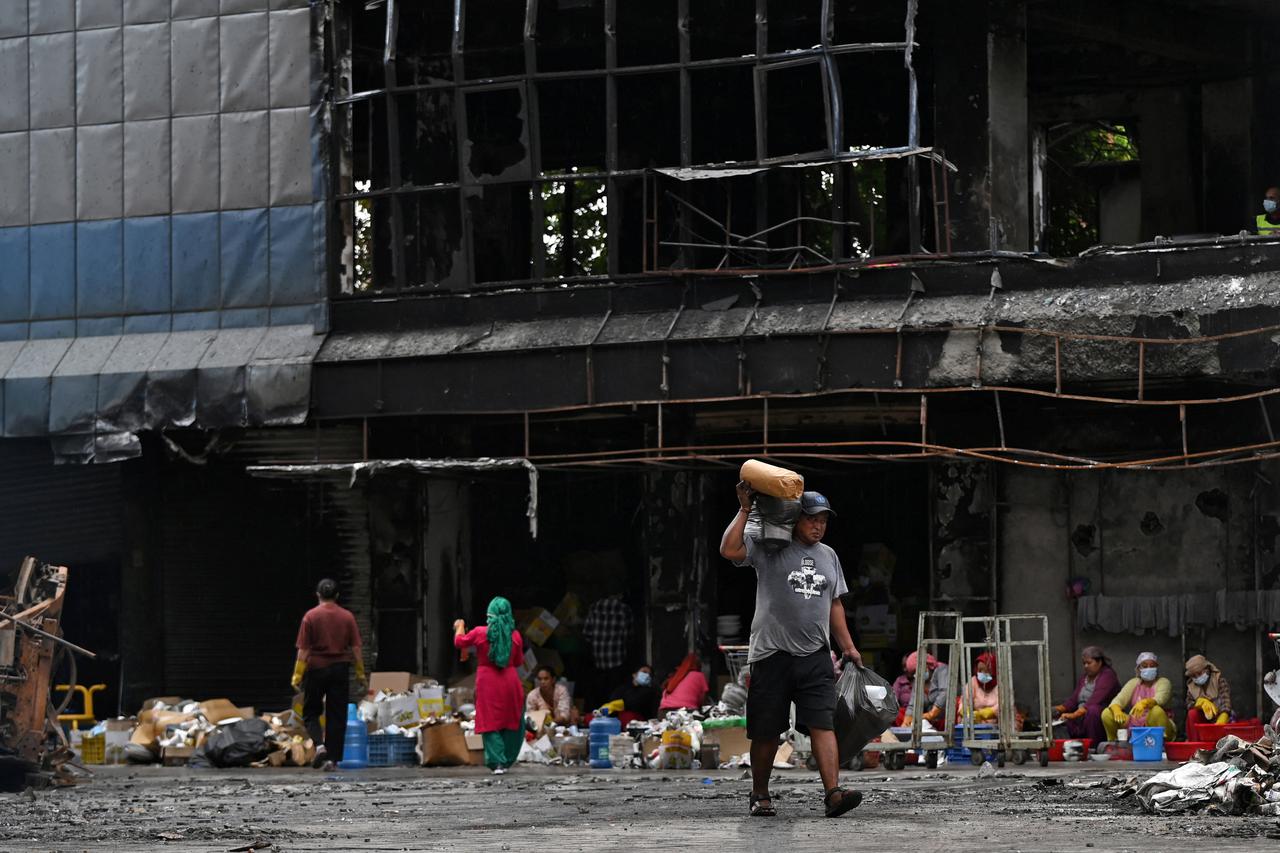 Workers salvage goods in front of Bhat-Bhateni, a departmental store that was damaged during recent protests, in Kathmandu
