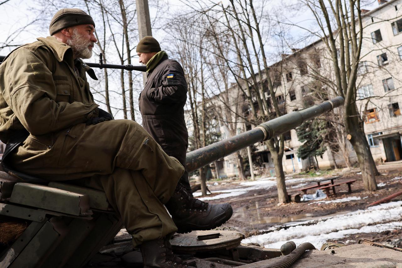 Ukrainian servicemen stand atop a tank, near the bombed-out eastern city of Bakhmut