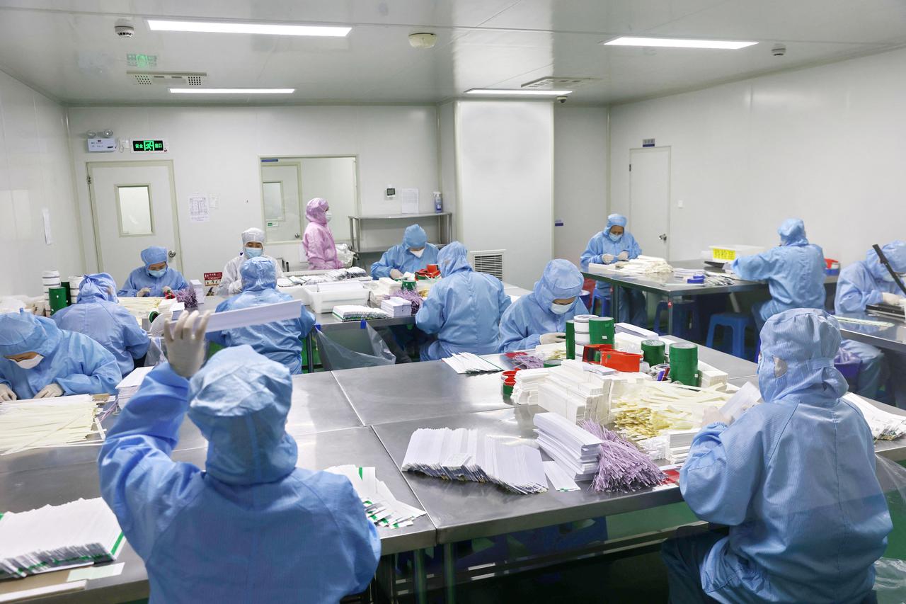 Workers work on manufacturing antigen testing kits for the COVID-19, at a workshop in Nantong