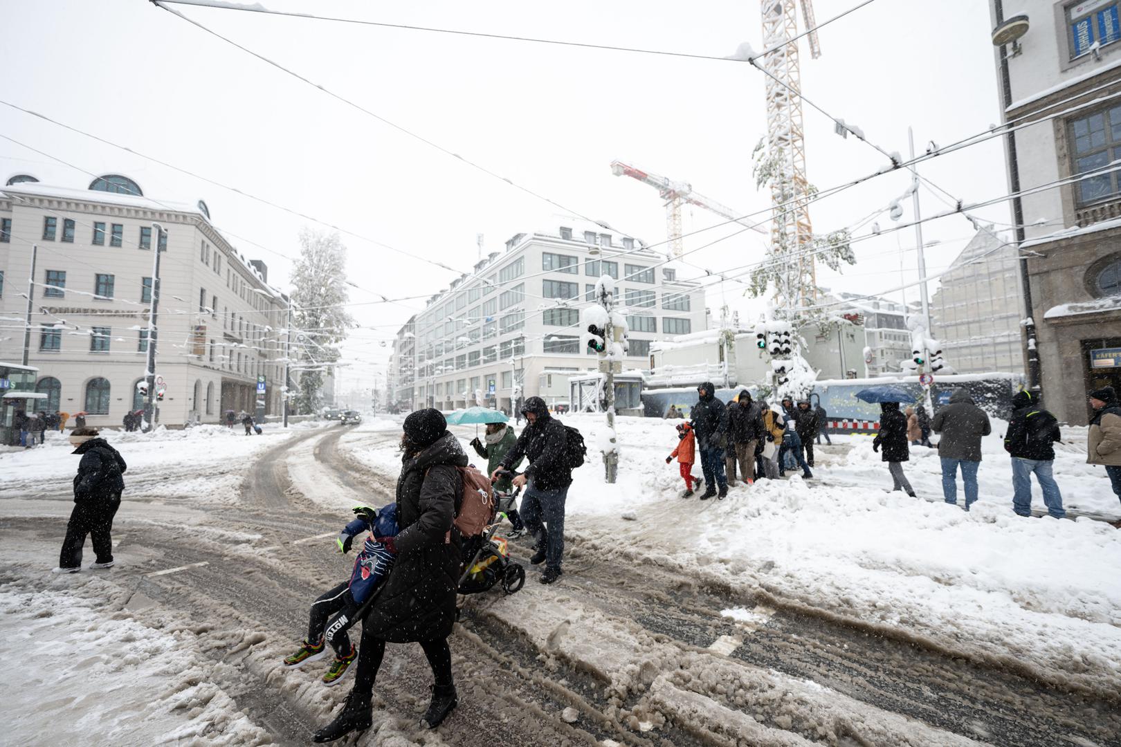 02 December 2023, Bavaria, Munich: Travelers cross a snow-covered street in front of the main train station. Snow and ice have caused chaos on the roads and on the railroads in southern Bavaria. Photo: Lukas Barth/dpa Photo: Lukas Barth/DPA