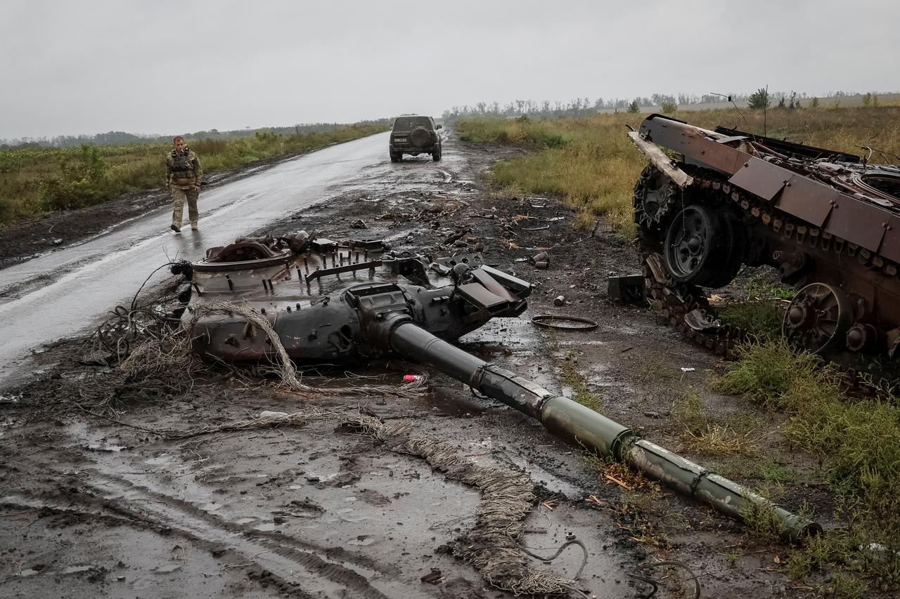 Ukrainian serviceman passes by a destroyed Russian tank near the village of Dolyna