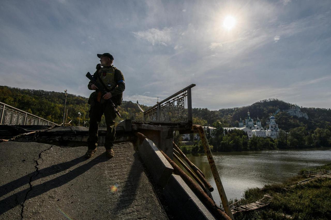 Service member of Ukraine's National Guard stands at a destroyed bridge over the Siverskyi Donets river in the town of Sviatohirsk