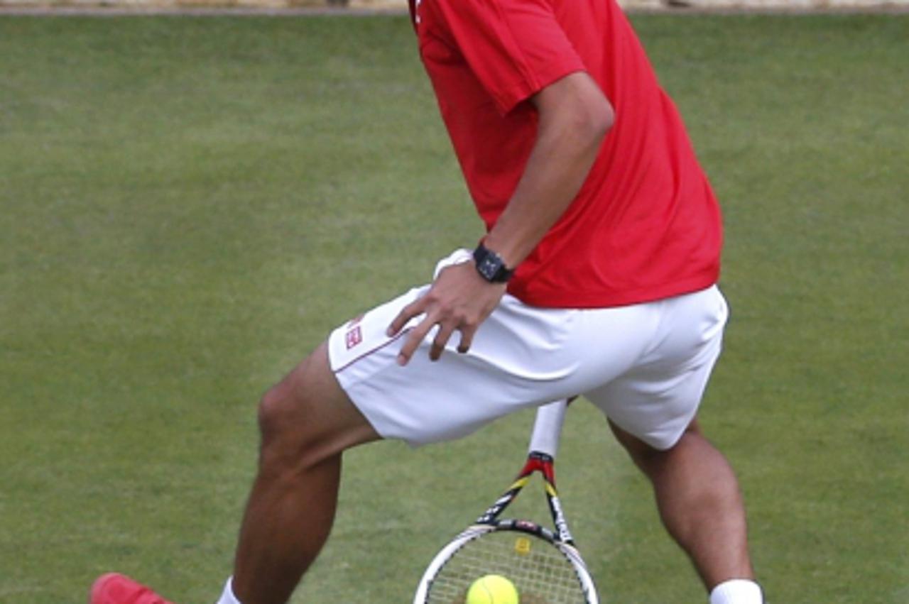 'Japan\'s Kei Nishikori hits a through the legs return as he and Go Soeda (not pictured) face Switzerland\'s Roger Federer and Stanislas Wawrinka in their men\'s doubles tennis match at the All Englan