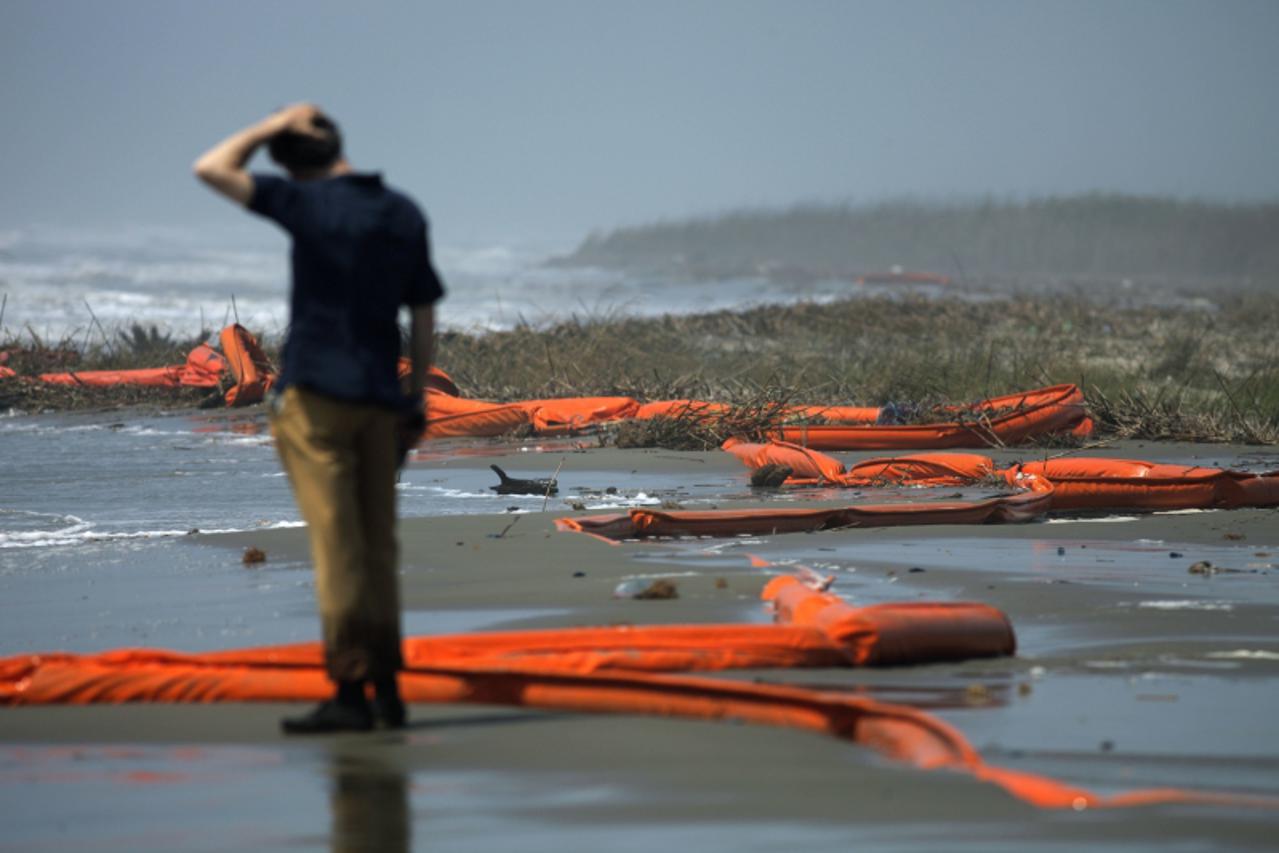 'A television reporter stands beside oil booms at the coast of South Pass, south of Venice, Louisiana, as oil leaking from the Deepwater Horizon wellhead continues to spread in the Gulf of Mexico, May