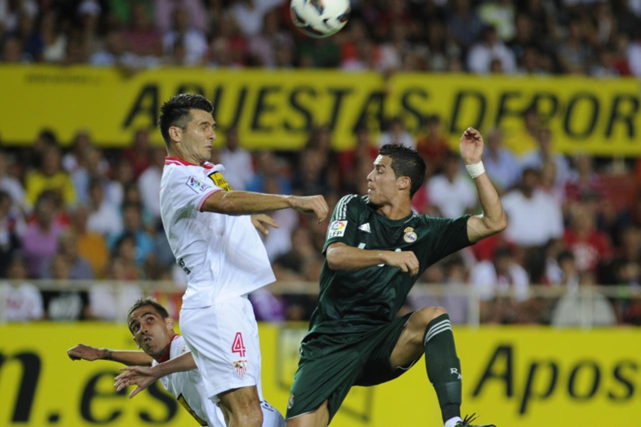 'Real Madrid\'s Cristiano Ronaldo (R) vies for the ball with Sevilla\'s Emir Spahic (C) during the Spanish league football match between Sevilla and Real Madrid at the Sanchez Pizjuan stadium in Sevil