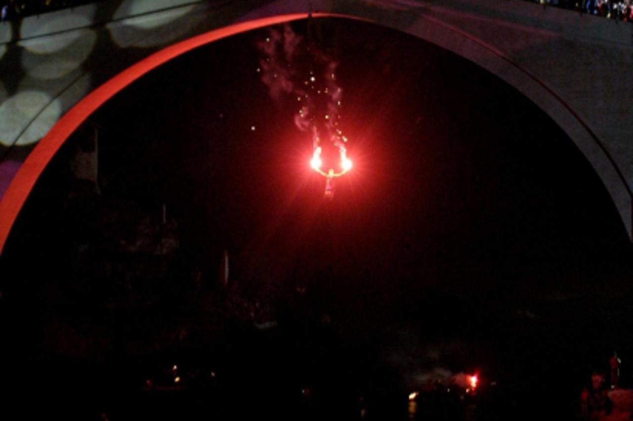 'A young Mostar man with torches in his hands jumps, 23 July 2004 in Mostar from the newly inaugaurated replica of the 16th century bridge destroyed by Bosnian Croat artillery in 1993 during armed eth