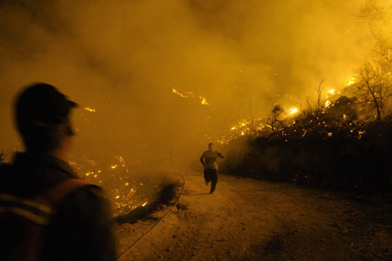 \'An Israeli firefighter runs from raging fire in Beit Oren, Carmel Forest, near Israel\'s northern city of Haifa on December 02, 2010. Around 40 people are believed to have been killed in the devasta