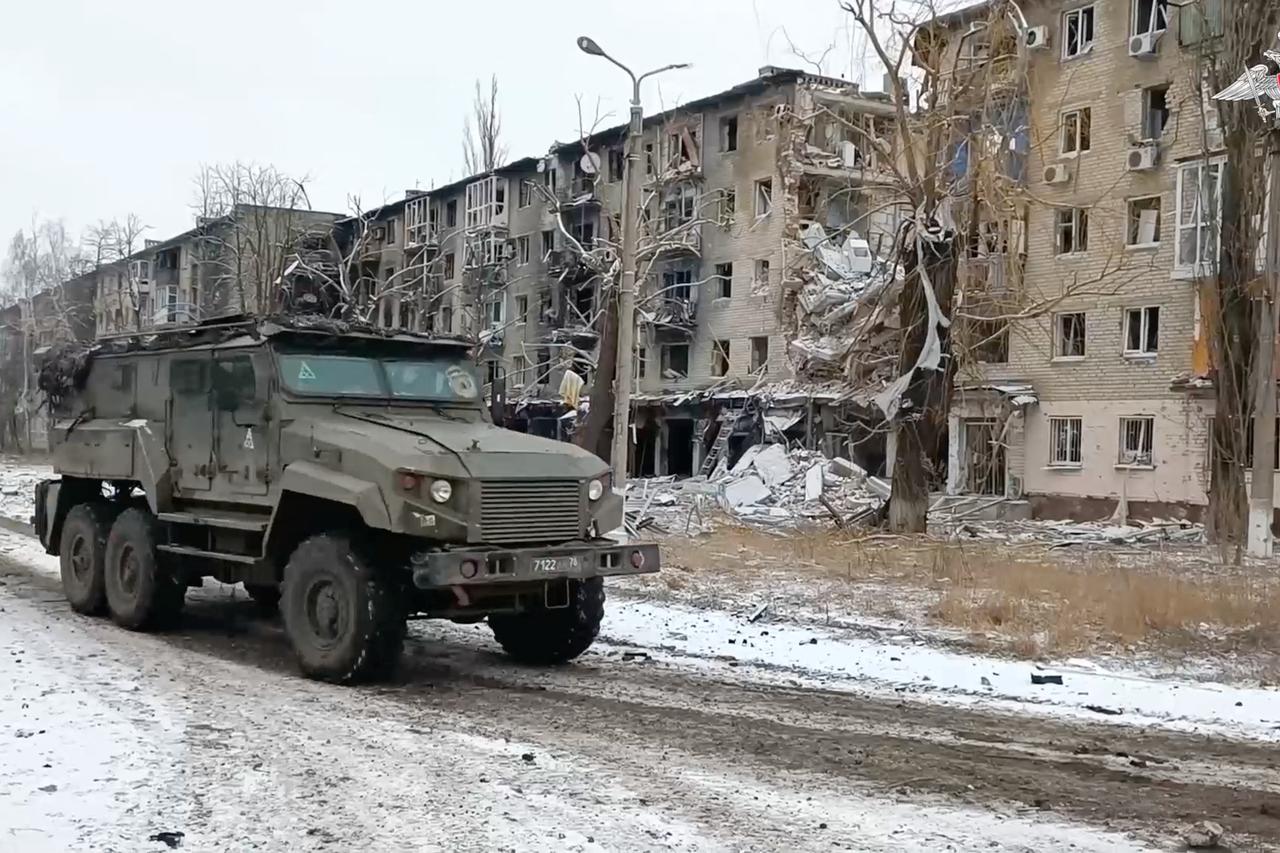 A military vehicle drives past damaged residential buildings in Avdiivka